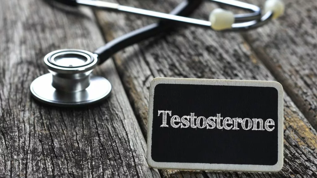 Grafika przedstawia stetoskop lekarski wraz z tabliczką z napisem "testosterone" oznaczającą "testosteron"